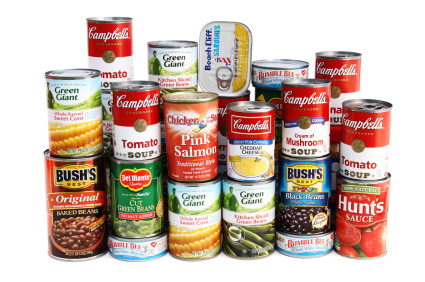 A stack of canned soups, vegetables, beans and fish